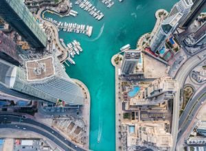 Aerial view of Dubai Marina futuristic skyline with man made lake in the middle and luxury yachts docked on the pier. The Dubai Marina is the world's first man made marina with luxury residences, offices and hotels.
