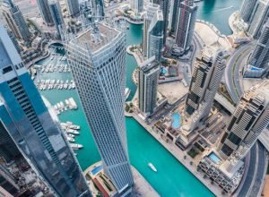 Aerial view of Dubai Marina futuristic skyline with man made lake in the middle and luxury yachts docked on the pier. The Dubai Marina is the world's first man made marina with luxury residences, offices and hotels.